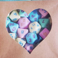 a box with a heart shaped hole, seen through it pastel coloured dice of all shapes